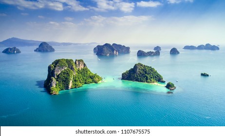 タイ、プーケットのヤオノイ島の周辺の島々は、青とターコイズ ブルーの海に緑豊かな熱帯の島で、背景に島々があり、太陽の光が透けて見える雲、無人機の航空写真