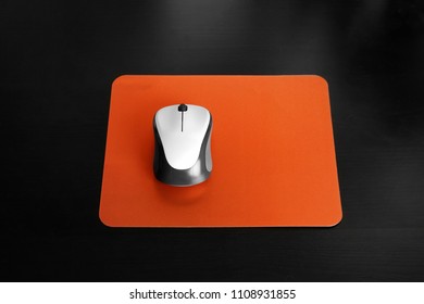 Almohadilla en blanco y mouse de computadora inalámbrico sobre fondo negro