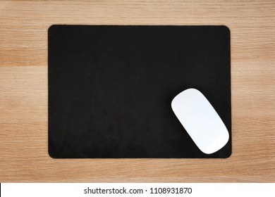 Blank pad and wireless computer mouse on wooden background, top view