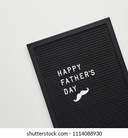 Schwarzes Letterboard mit weißen Kunststoffbuchstaben mit Zitat Happy Father's Day, auf weißem Hintergrund. Flache Lage, quadratischer Schnitt.