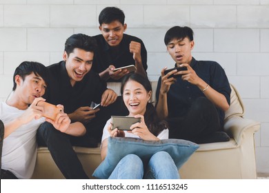 Groep vrienden die plezier hebben in de woonkamer en naar een smartphone kijken, Aziatische tiener die naar een voetbalwedstrijd in Mobilephone kijkt