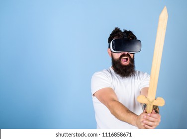 VR-gamerconcept. Man met display op het hoofd en zwaardvechtspel in VR. Hipster op schreeuwend gezicht geniet van spel in virtual reality. Man met baard in Vr-bril, lichtblauwe achtergrond.