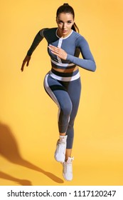 Mooie vrouw loper in silhouet op gele achtergrond. Foto van sportieve vrouw in modieuze sportkleding. Dynamische beweging. Kracht en motivatie. Volledige lengte