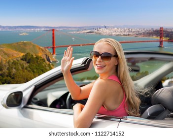 reizen, road trip en mensen concept - gelukkige jonge vrouw in converteerbare auto zwaaien hand over golden gate bridge in de baai van san francisco achtergrond