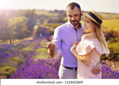 Schattig jong koppel verliefd op een veld van lavendel bloemen. Geniet van een moment van geluk en liefde in een lavendelveld. Een paar minnaars die een vlinder houden. Verliefd zijn. Liefde.