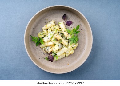 Ensalada de papas tradicional alemana de estilo moderno con espárragos blancos y pepinillos en primer plano en un plato con espacio para copiar