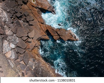 Loftopnam vun uewen op Mierwellen, déi op Fielsen um Strand mat türkisbloem Mierwaasser schloen. Wonnerbar Fielskliffenlandschaft un der portugisescher Küst. Drohnenopnam.