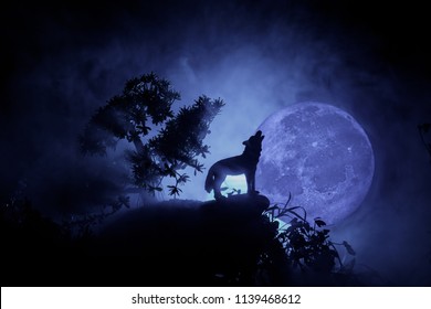 暗いトーンの霧の背景と満月に対して遠吠えするオオカミのシルエット、または満月に遠吠えするシルエットのオオカミ。ハロウィーン ホラーのコンセプトです。セレクティブ フォーカス