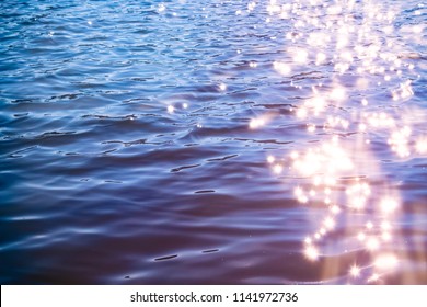 Sunlight twinkling off river water with small waves. Calm summer evening. Colorful background