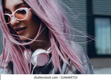 ヘッドフォン、ストリート スタイル、屋外のポートレート、流行に敏感な女の子、音楽、mp3、バリ、美容女性、サングラス、オレンジ色、コンセプトで音楽を聴く紫ピンクの髪を持つ美しい少女