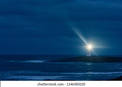 Lighthouse at night under heavy cloud on dark peninsula