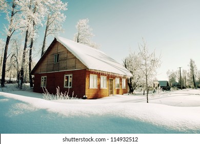 朝のロシアの田舎の雪に覆われた丘、赤い木造の家の窓が東を向いた