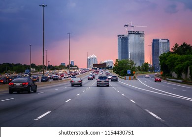 夜の交通。典型的な忙しいアメリカの都市で日没の夜に高速道路上の車。赤、黄、青の空の雲を持つ美しい素晴らしい夜景。ダウンタウンの日没。