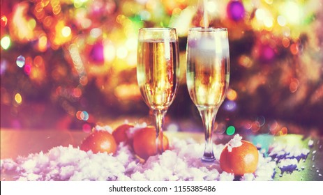 Selamat Natal dan Tahun Baru 2021. Dua gelas sampanye dengan latar belakang Natal kabur.