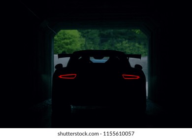 Silhouette of supercar in tunnel with stop lights. Rear view of supercar