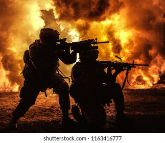 Silhouetten von zwei Armeesoldaten, US-Marinesoldaten in Aktion, umzingelten Feuer und Rauch, schossen mit Sturmgewehr und Maschinengewehr und griffen den Feind während einer Offensivmission mit unterdrückendem Gewehrfeuer an