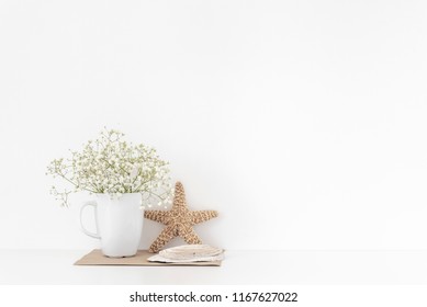 Achtergrond met stationair, schelpen, sea star, boeket van witte bloemen in mok op witte muur achtergrond, schattig zacht huisdecor. Kopieer ruimte voor tekst. Lege ruimte voor belettering. Goede koop zomer