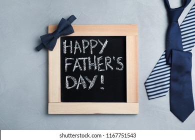 灰色の背景に黒板とネクタイを使用したフラットレイコンポジション。父の日おめでとう