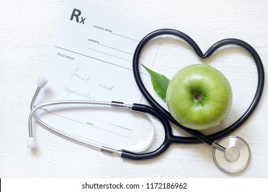 Gesundes Zeichenkonzept der alternativen Medizin mit Stethoskopherz und grünem Apfel auf weißem Hintergrund