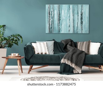 Gedessineerde kussens op de bank naast houten tafel en plant in donker appartement interieur. Echte foto