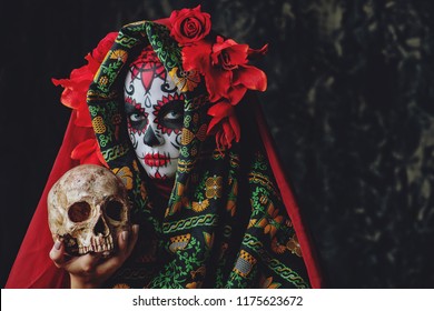Calavera Catrina sosteniendo una calavera sobre un fondo oscuro y aterrador. Maquillaje de calavera de azúcar. Dia de los muertos. Dia de los Muertos. Víspera de Todos los Santos.