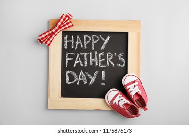 Composición plana con pizarra y zapatos de bebé sobre fondo gris. Feliz Día del Padre