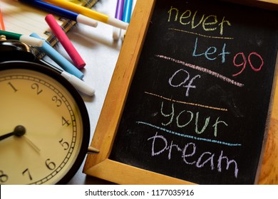 Laat je droom nooit los op zin kleurrijk handgeschreven op schoolbord, wekker met motivatie en onderwijsconcepten