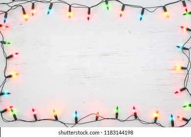Weihnachtslichtbirnenrahmendekoration auf weißem Holz. Feiertagshintergrund der frohen Weihnachten und des neuen Jahres. Ansicht von oben