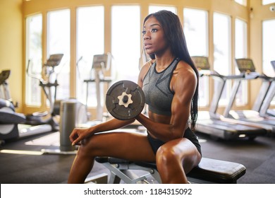 sterke afro-amerikaanse vrouw die gewichten heft in de sportschool