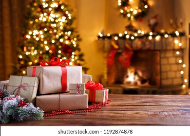 Weihnachtsgeschenke auf Holztisch geschmückter Tannenbaum und Kamin Winterurlaub Konzept