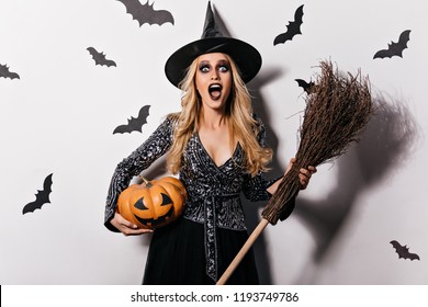 Surprised blonde girl screaming on white background with bats. Gorgeous young witch chilling at vampire party.