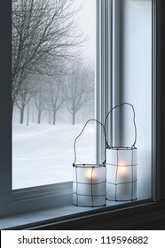Gezellige lantaarns op een vensterbank, met winterlandschap gezien door het raam.