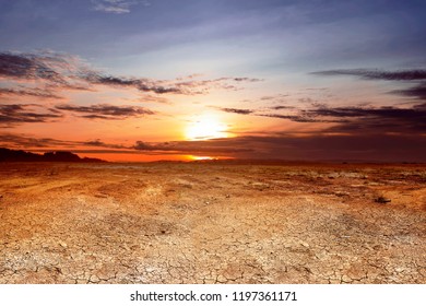 Dry land with cracked ground and dramatic sky at sunset