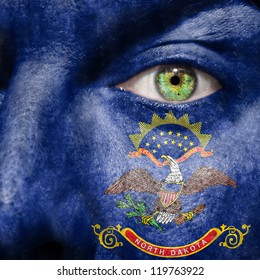 Flag painted on face with green eye to show North Dakota support