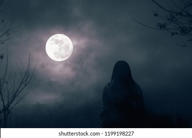 雲のある夜空に対する乾いた木々のシルエットと、夜だけで満月を見る女性、自然の背景
