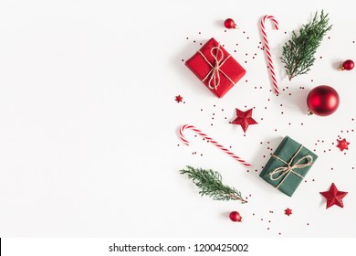 Weihnachtskomposition. Geschenke, Tannenzweige, rote Verzierungen auf weißem Hintergrund. Weihnachts-, Winter-, Neujahrskonzept. Flache Lage, Draufsicht, Kopierraum