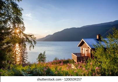 Casa de verano de madera noruega (Hytte) con terraza con vistas al pintoresco lago al atardecer, Telemark, Noruega, Escandinavia