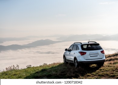 SUV-voertuig op de top van een berg met wolken op zonsondergang.