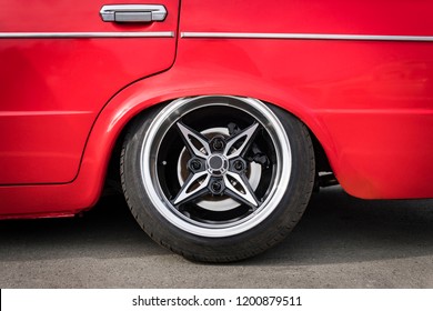 Virum Auto fir déi ënnescht Suspension un de Buedem unzepassen. Säit Vue op neit Luxus Auto Rad op Sëlwer Metal Felge mat schwaarze Glanz Pneuen. Luxus Sport Auto Rad mat niddereg Profil Pneuen. Auto Tuning,