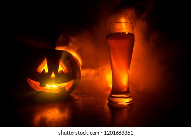 Glas koud licht bier met pompoen op een houten tafel voor Halloween. Glas vers bier en pompoen op een donker getinte mistige achtergrond