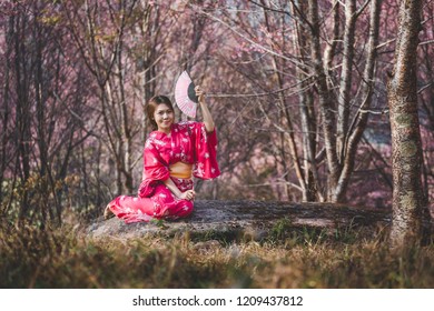 桜の花を背景に日本の着物を着た幸せなアジア人女性