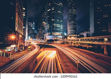 夜の香港の通りの交通。オフィスの超高層ビルと高速道路の交通量が多く、車のライトトレイルがぼやけています。香港、中国
