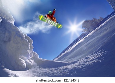 青い空を背景にジャンプするスノーボーダー