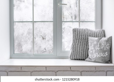 Vida invernal acogedora y helada: té o café caliente decoración de tejido de lana caliente en el alféizar de la ventana contra el paisaje nevado desde el exterior.