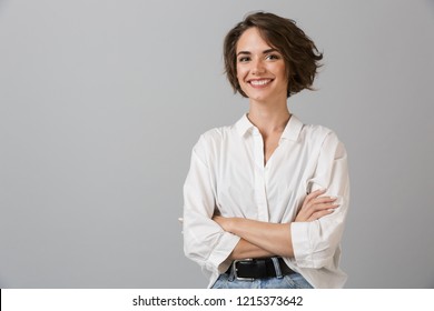 灰色の壁の背景に分離されたポーズをとって幸せな若いビジネス女性のイメージ。