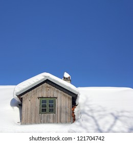 El viejo techo de madera cubierto de nieve y cielo azul