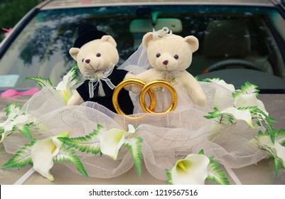 Hochzeitsbären sitzen auf der Motorhaube eines Hochzeitsautos. Hochzeitsspielzeug. Winnie Puuh und Ferkel. Liebe.
