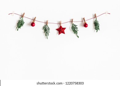 Chrëschtkompositioun. Girland aus roude Kugelen a Tannenbamzweiger op wäissem Hannergrond. Chrëschtdag, Wanter, Neijoerskonzept. Flaach geluecht, Vue vun uewen, Kopierraum