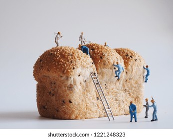 Ciérrese encima de gente miniatura muchos del hombre del trabajador que trabaja en el fondo del pan integral, concepto del trabajo del equipo.