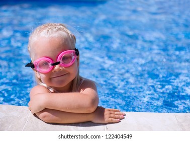 笑顔の女の赤ちゃんスイミング プールで水泳用メガネを着用